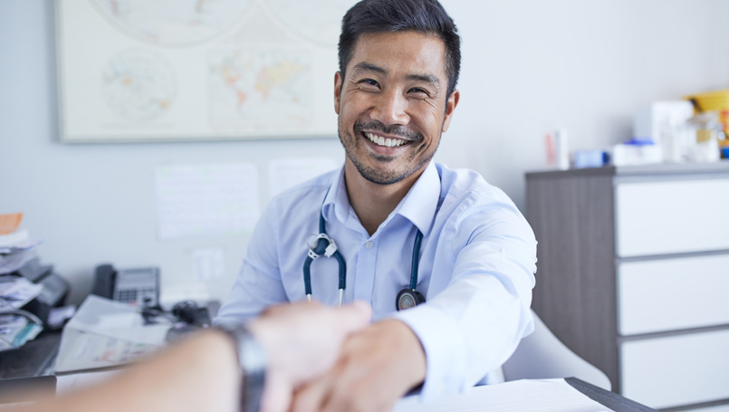 A smiling doctor shaking hands with a patient.